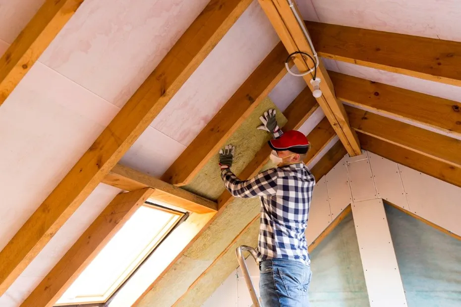 Contractor fitting batt insulation between roof rafters near a skylight in a Surprise, AZ home